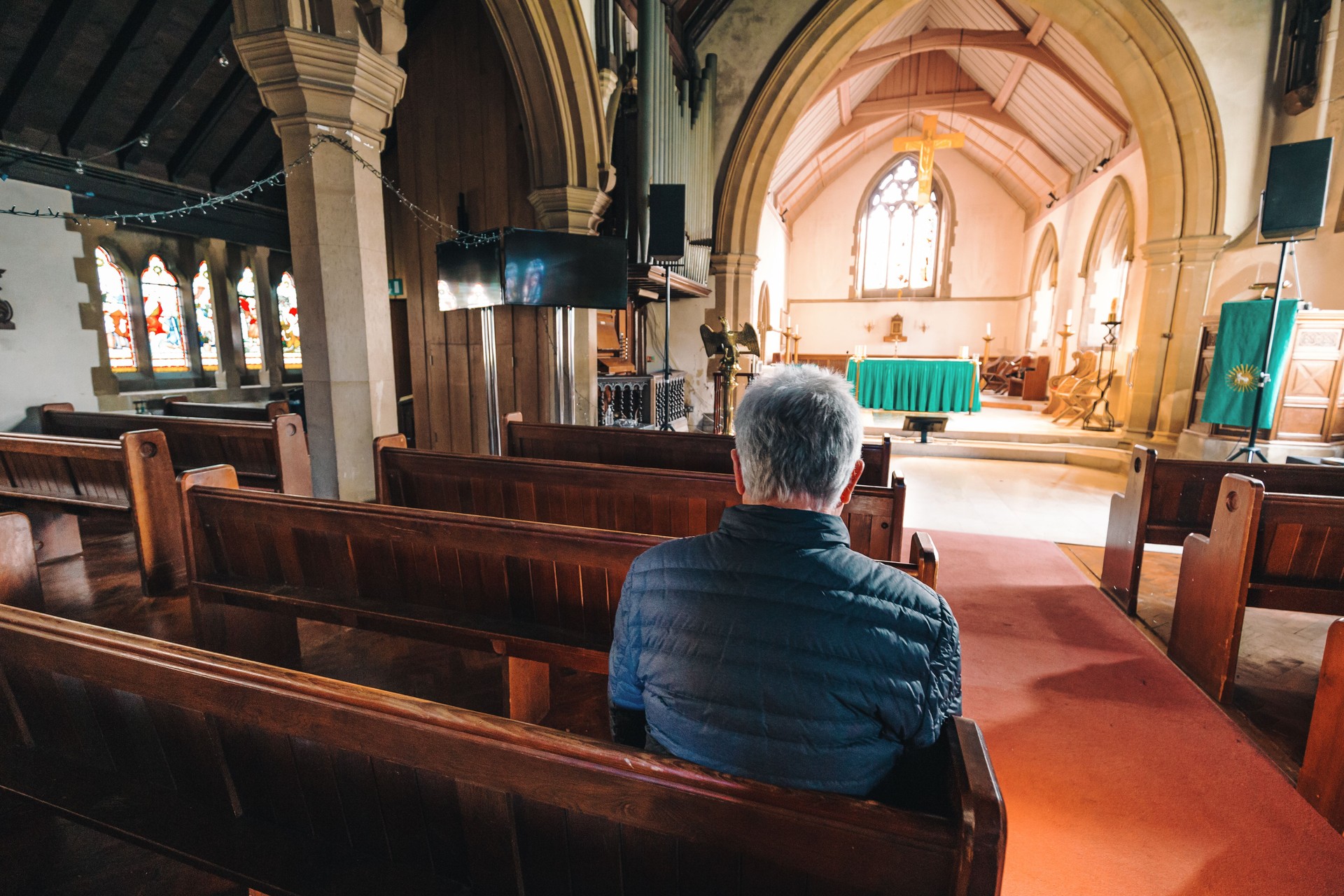 Senior man praying in ancient Anglican church