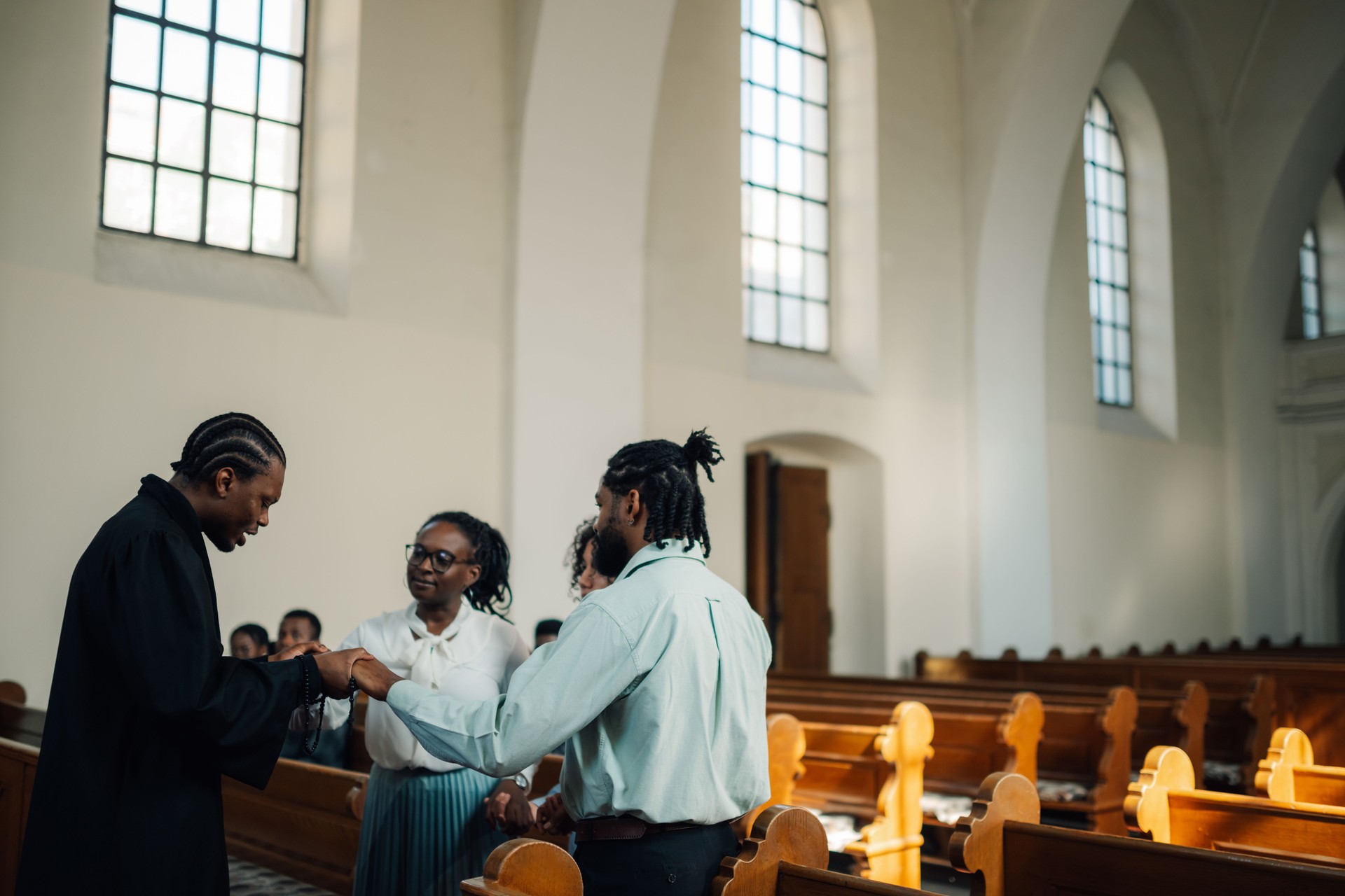Priest holding hands with congregation members praying in church
